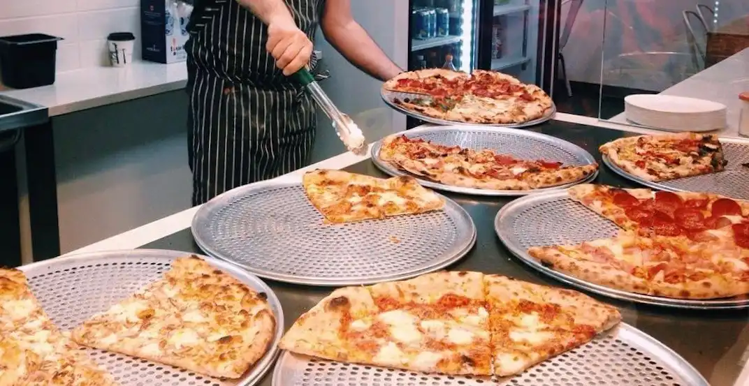 pizzeria employees preparing and baking pizzas